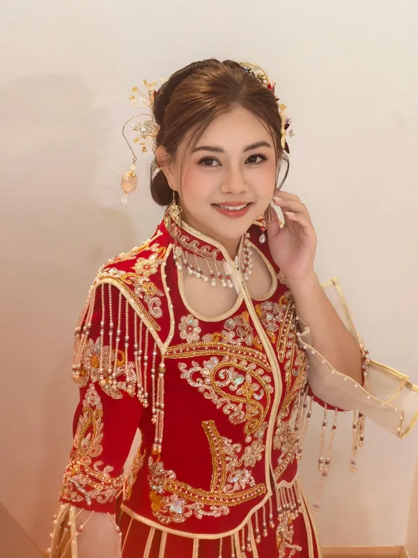 Smiling bride in beaded red Qun Kua with gold headpiece, bridal makeup by THEENG, Kuantan