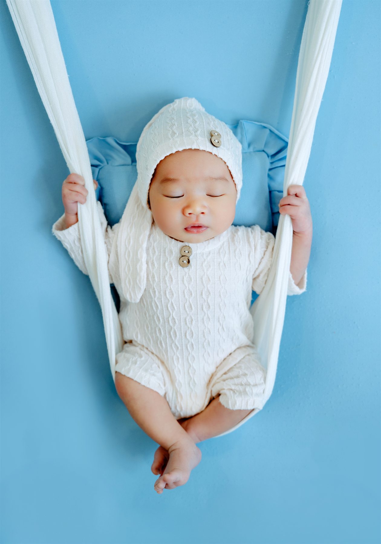 Newborn photography by Famous Bridal, sleeping baby in blue hammock setup