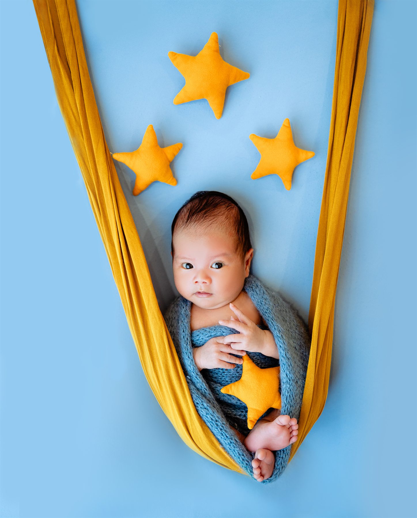 Newborn photography by Famous Bridal, baby portrait in blue and gold star hammock styling
