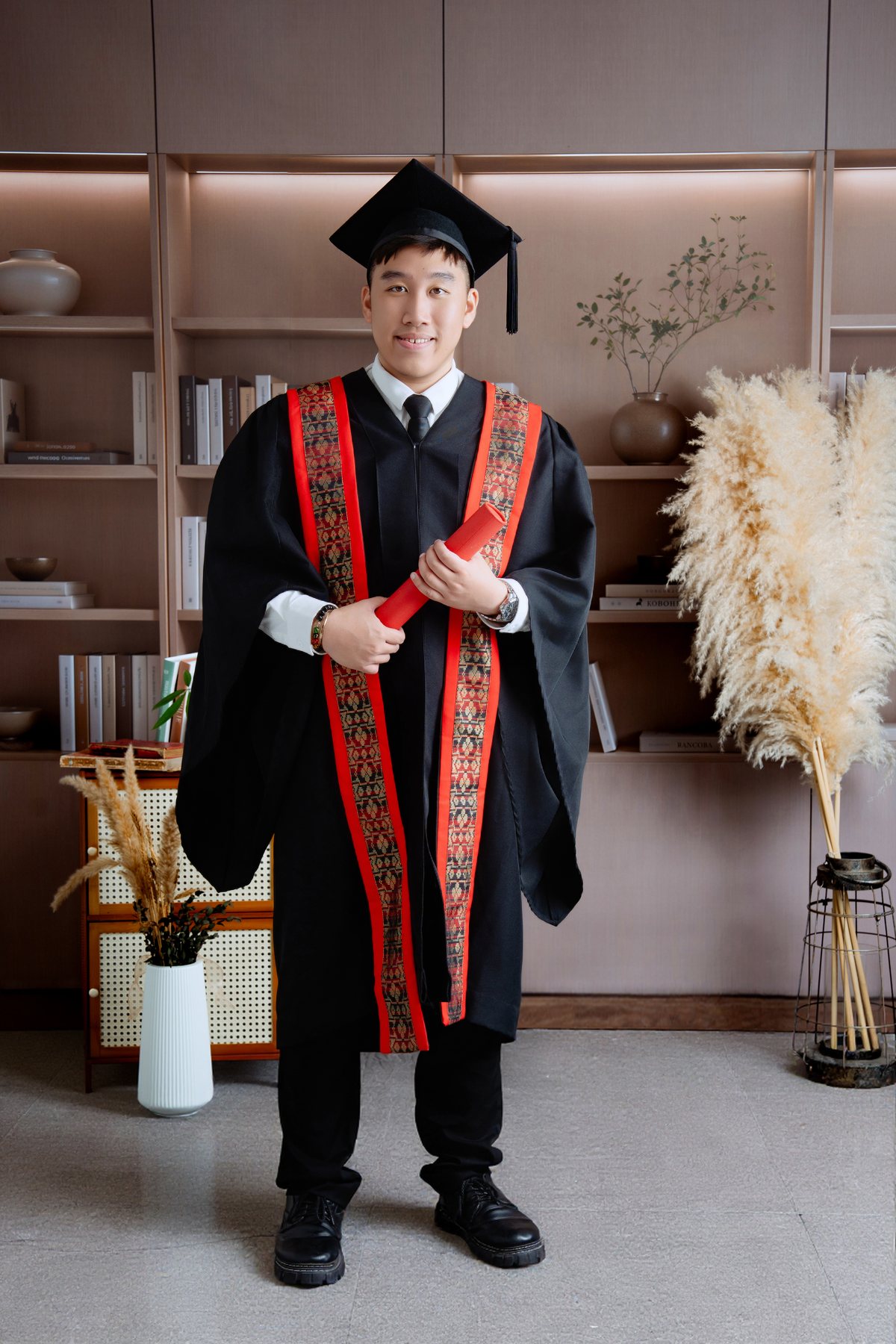 Standing graduate studio portrait with robe and cap