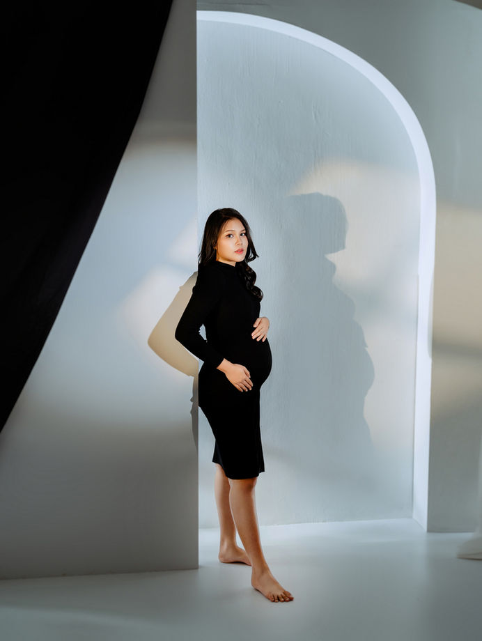 Elegant solo maternity portrait with studio arch light