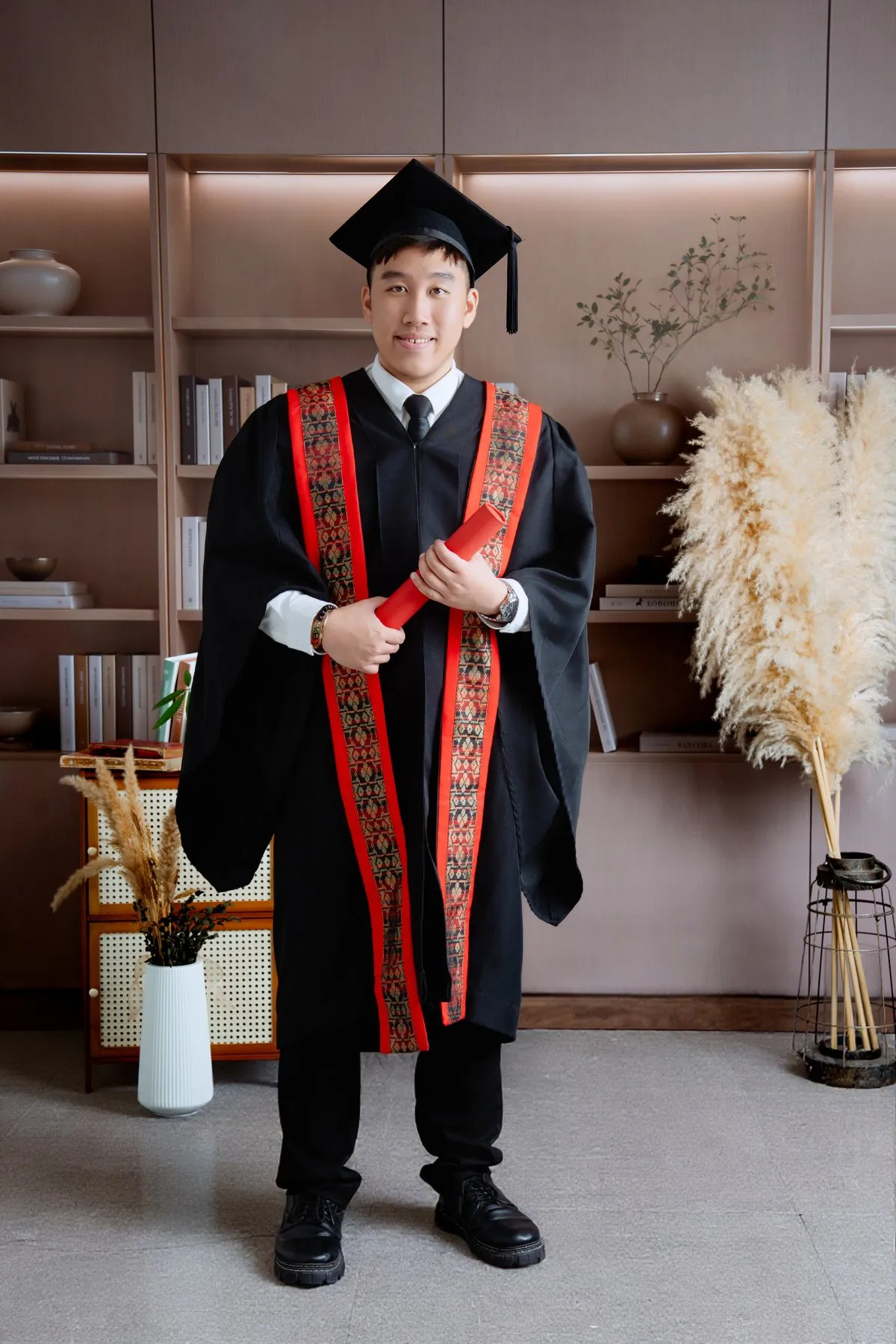 Standing graduate studio portrait with robe and cap